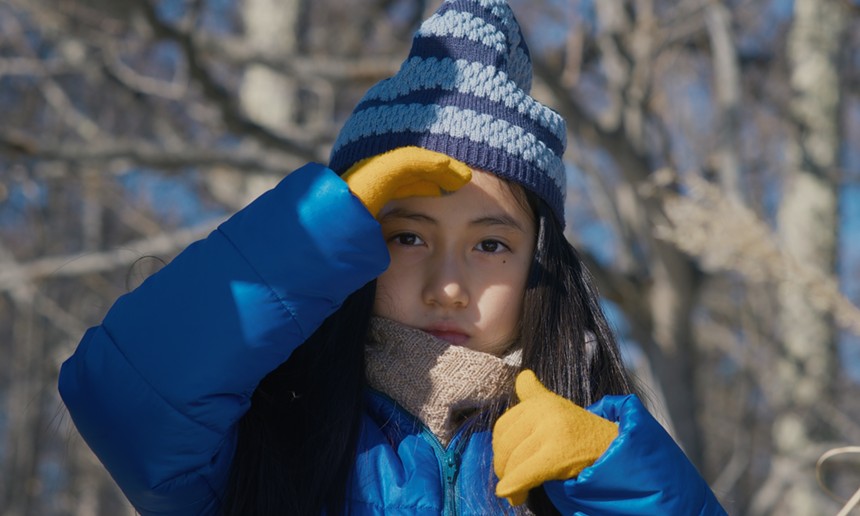 A child in a blue coat and yellow gloves