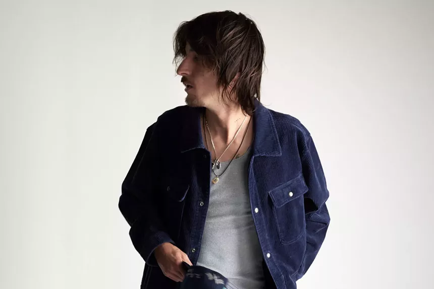 Danny Ocean looking away from the camera in a gray tank top and blue button-up shirt