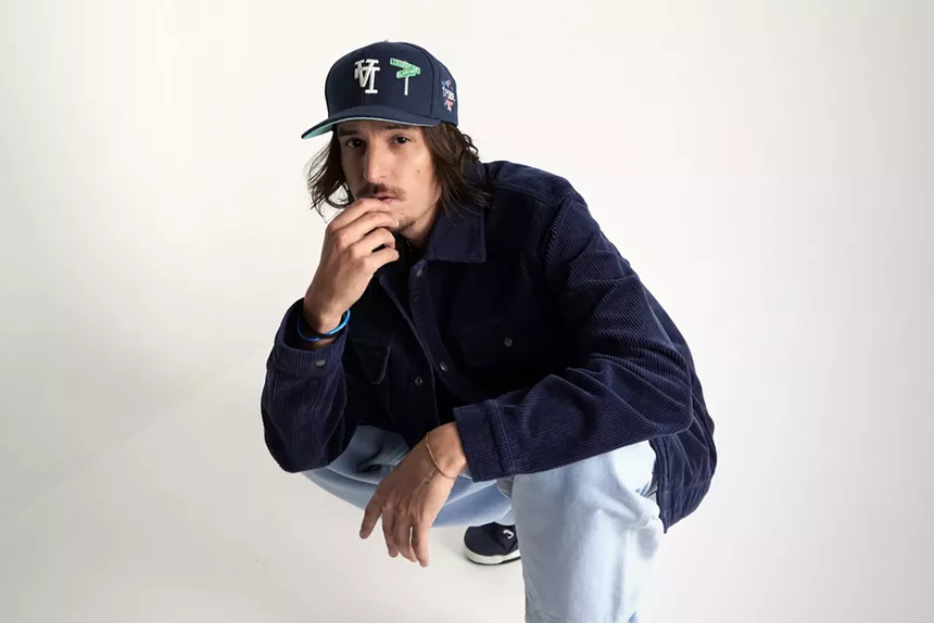 Danny Ocean crouched down with a baseball cap on his head.