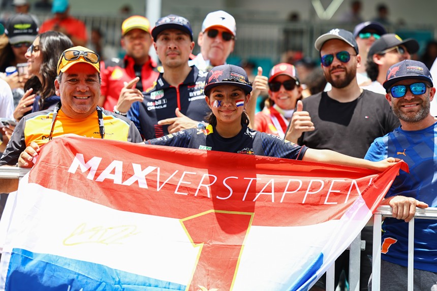 A fan holds a Dutch flag with the name "Max Verstappen" written on it