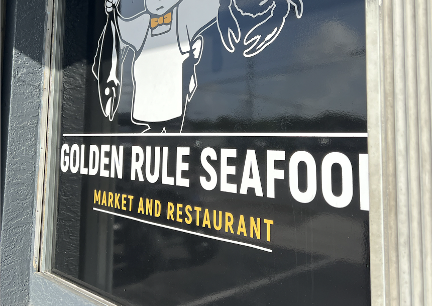 A sign on a glass window that reads "Golden Rule Seafood"