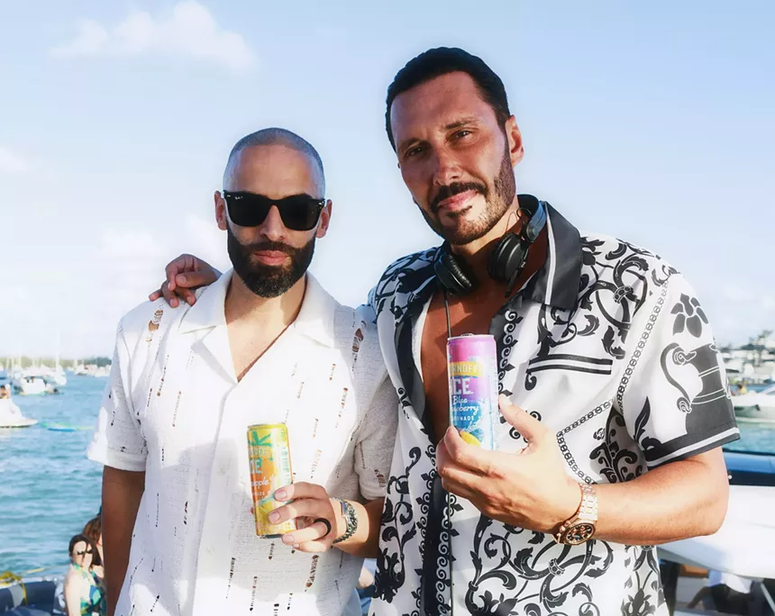 Two men holdings drinks on a boat