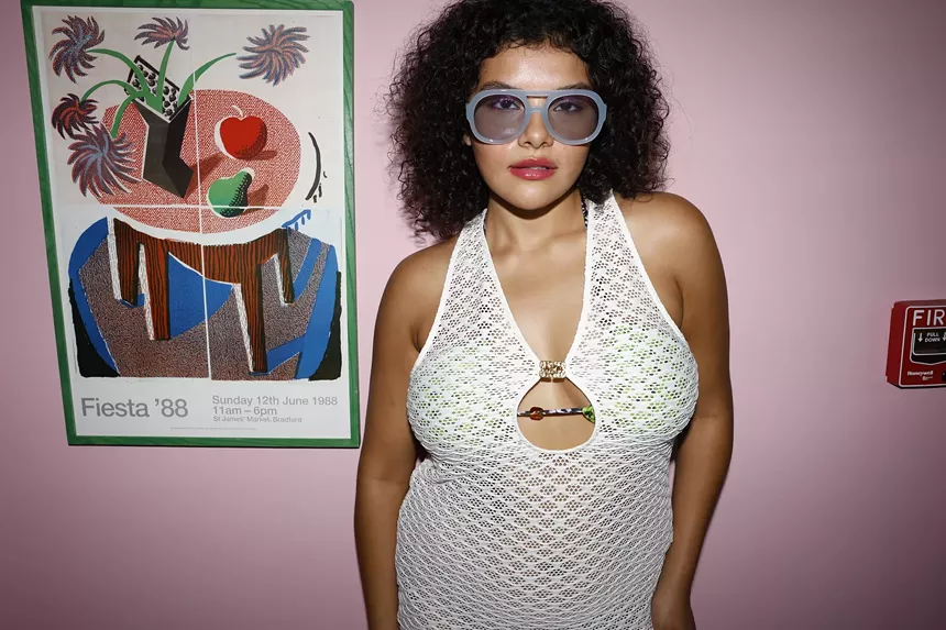 A woman against a pink wall in a knit swimwear