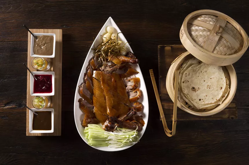 a platter of duck meat on a wooden table served in a white plate