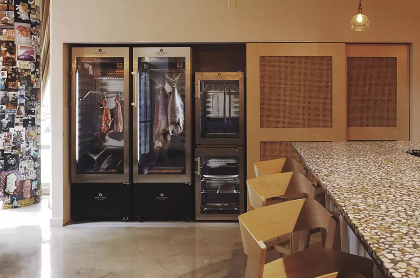 A dry age fridge and a sushi counter with wood tones