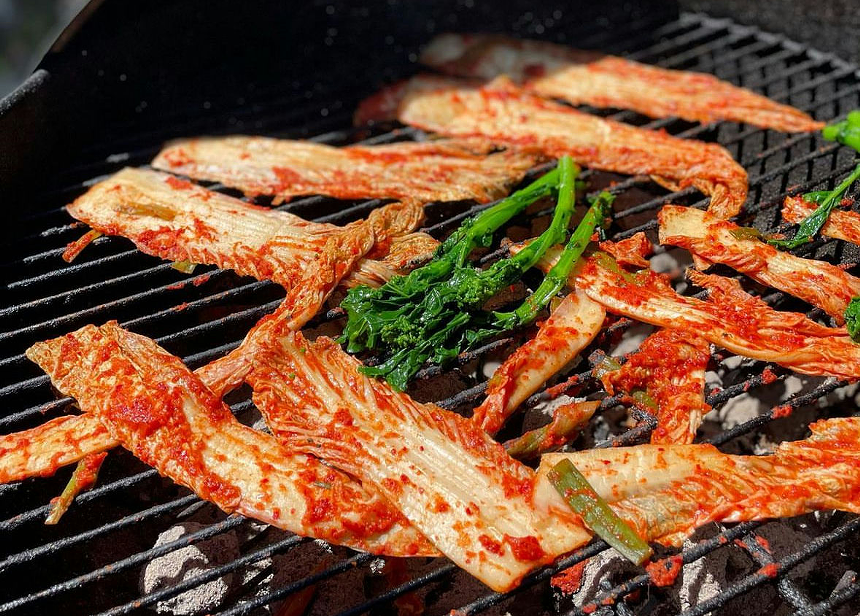 Kimchi on a black griddle with green asparagus