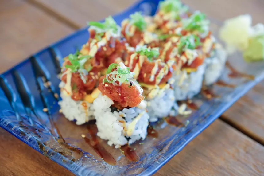 Sushi rolls on a blue platter with toppings