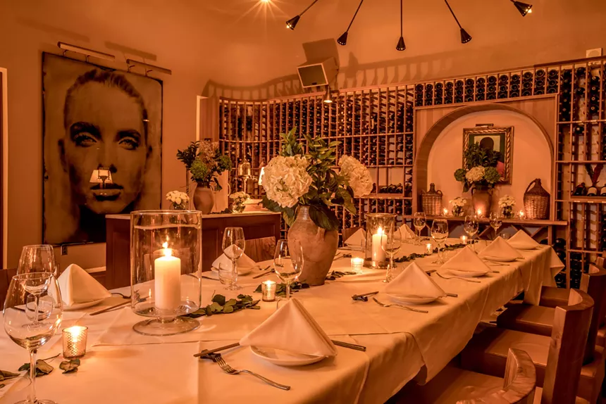 A long dining table with decor and velevet seating
