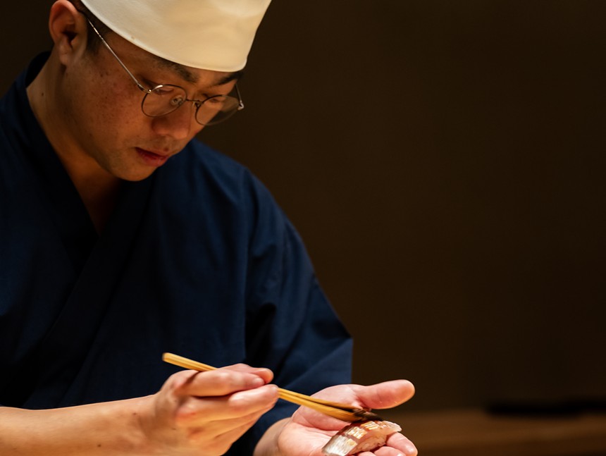 A man preparing nigiri with a chef outfit on