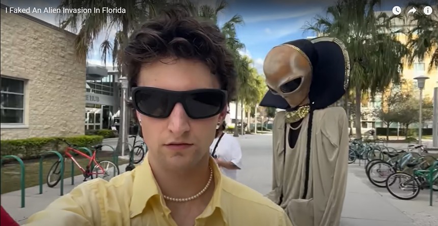 YouTube creator Anthony Po looks into camera with sunglasses on, with alien costume behind him