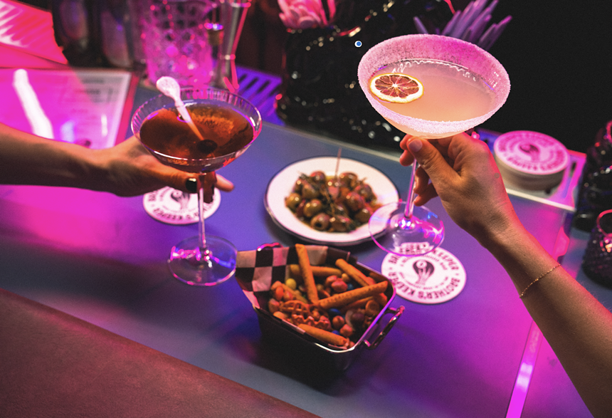 three cocktails and a plate full of olives on a purple table