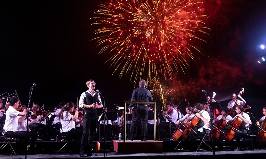 MMF Symphony Orchestra performing while fireworks burst in the sky