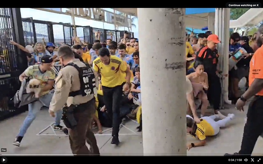 crowd scene in which a man frees a dog from a portable carrier