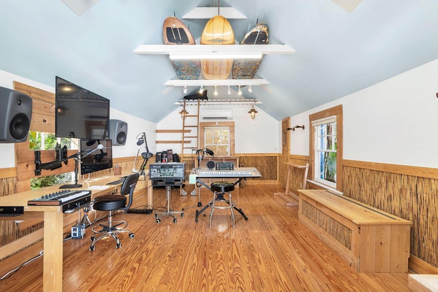 Studio inside Jimmy Buffet's bungalow, with polished wood floors and surfboards hanging overhead