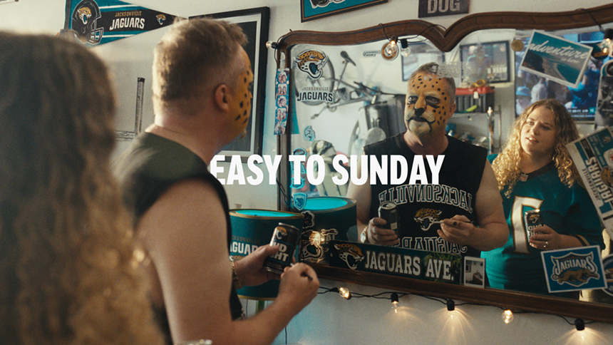 A Jacksonville Jaguars fan with team-themed face paint stares in mirror