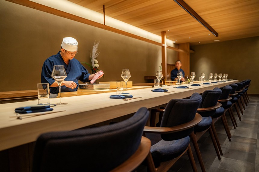 A man making sushi in a chef outfit behind a counter