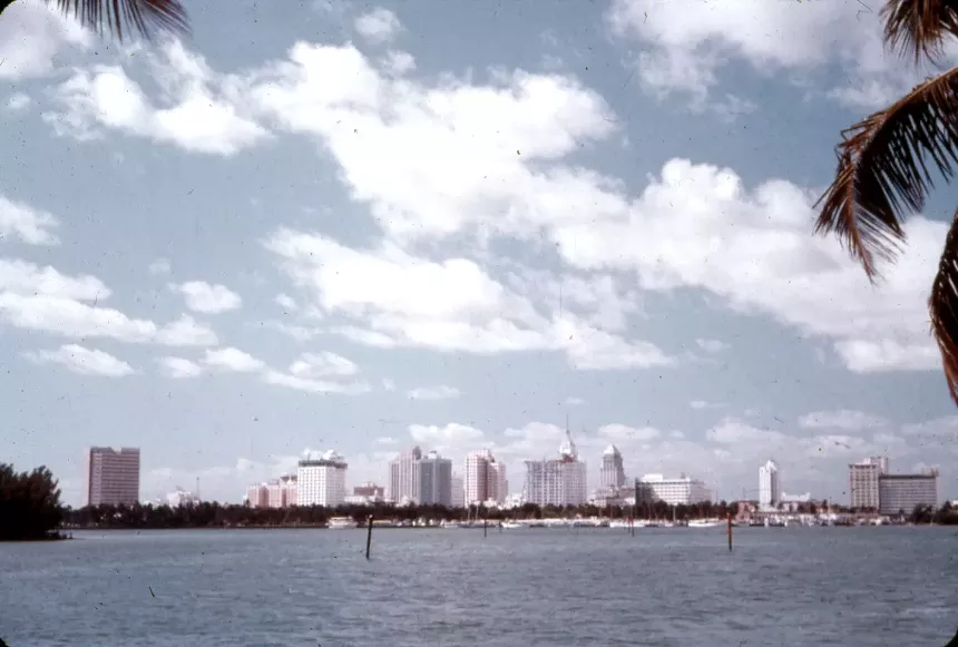 color photo of the downtown miami skyline on a sunny day with scattered clouds, foregrounded by biscayne bay
