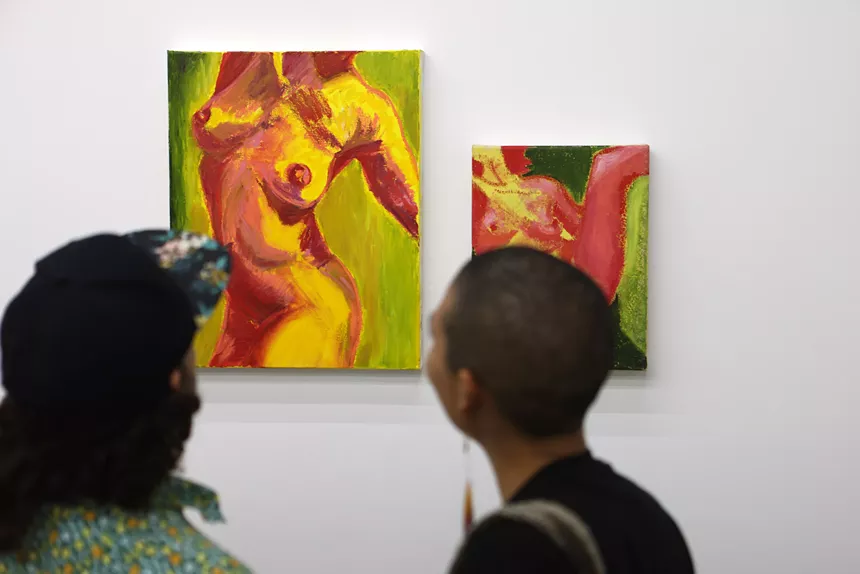 People looking at paintings hanging on a wall