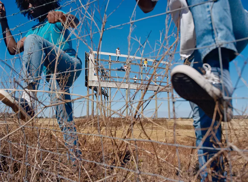 Boys climbing over a fence