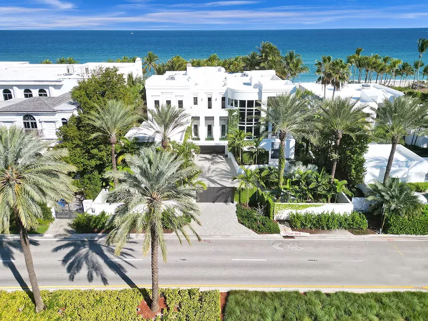 Color photo of a modern, white, beachfront home.