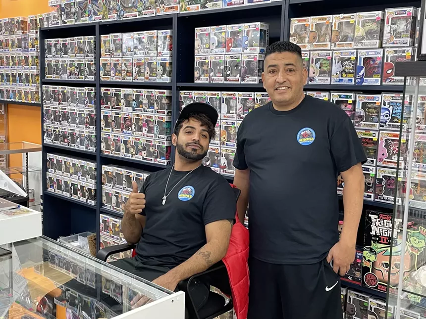 two men pose in a comic store