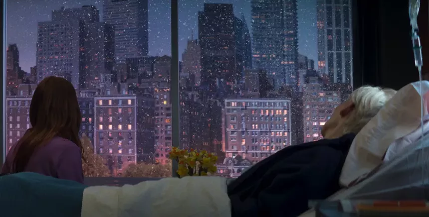 Two women look at buildings outside a window at dusk.