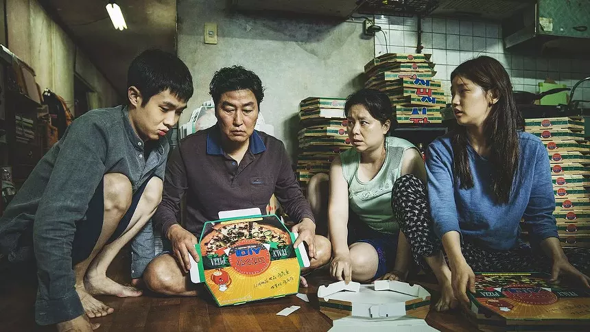 a Korean family sits surrounded by stacks of pizza boxes