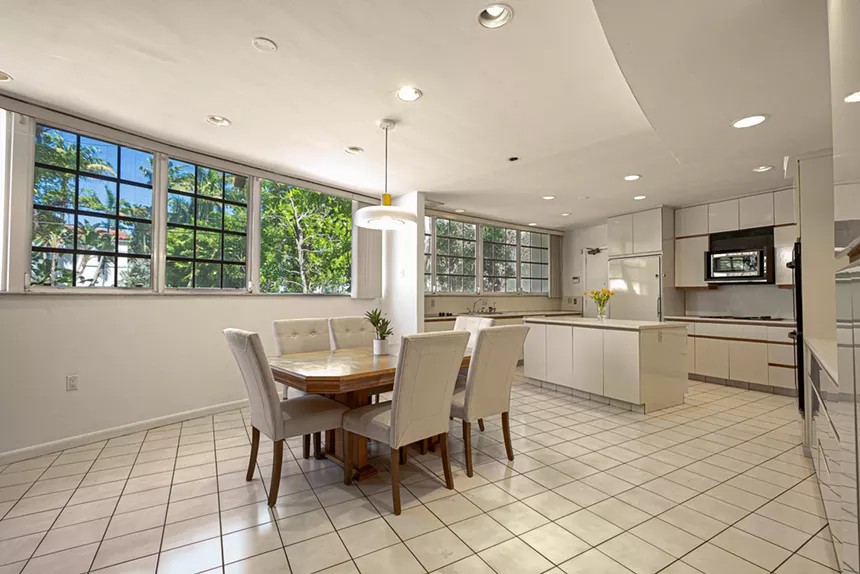 A mid-century modern kitchen with a dining table and large windows