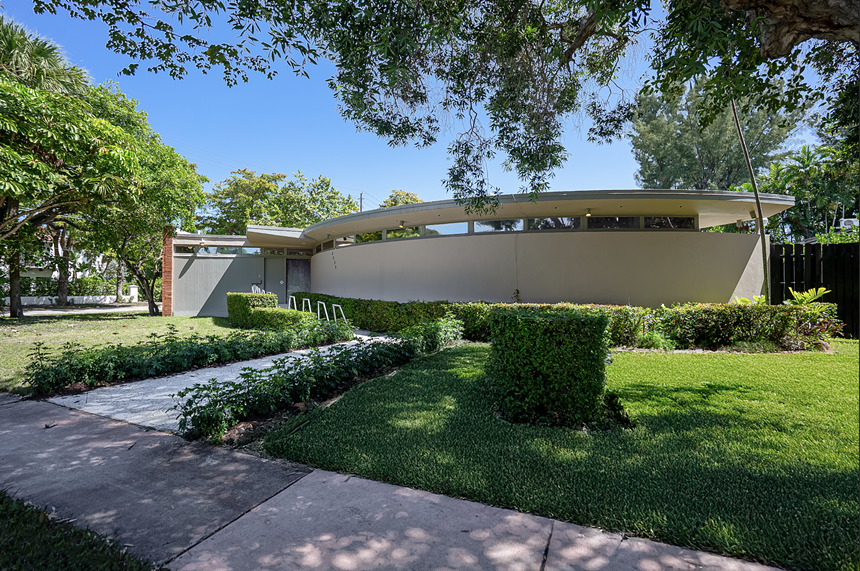 The outside of a beige circular home on a green lawn