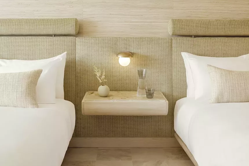 two hotel beds with a floating nightstand in between them