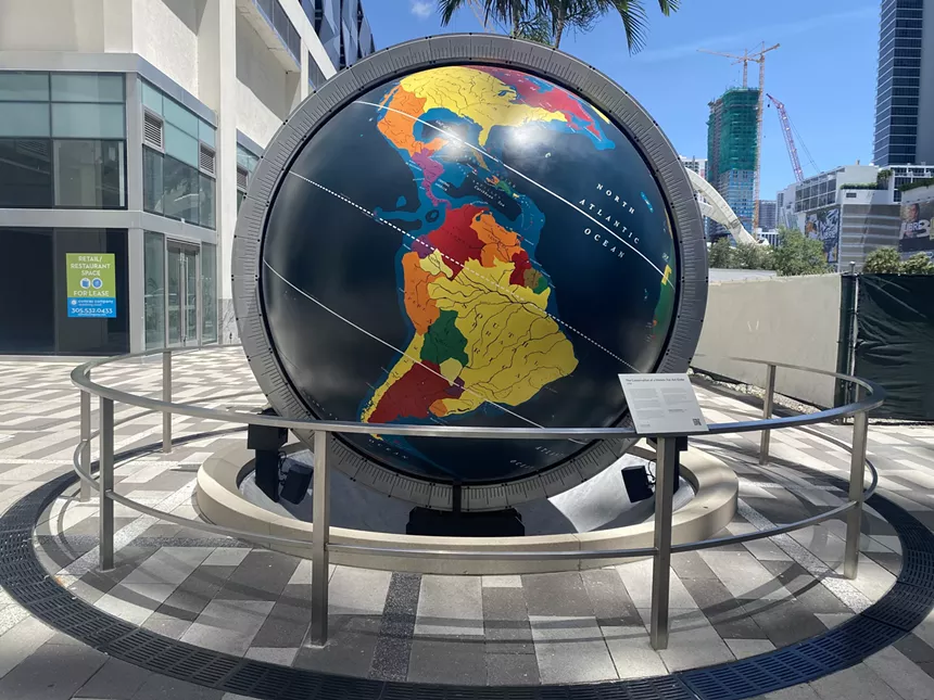 a giant globe on display at a public court in a shopping district