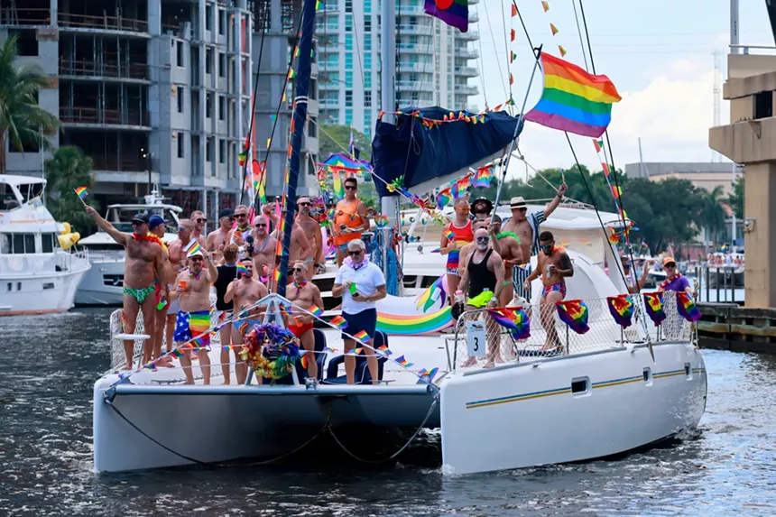 men in rainbow clothing party on a yacht decked out in rainbow flags