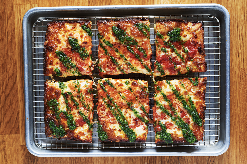 a pizza wiht toppings and green sauce