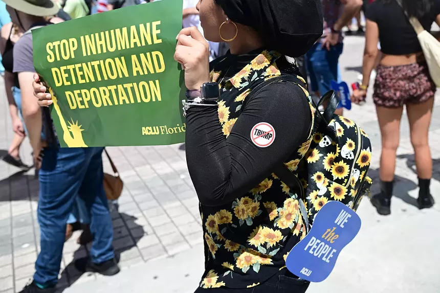 A protester holds up a sign reading, "Stop inhumane detention and deportation."
