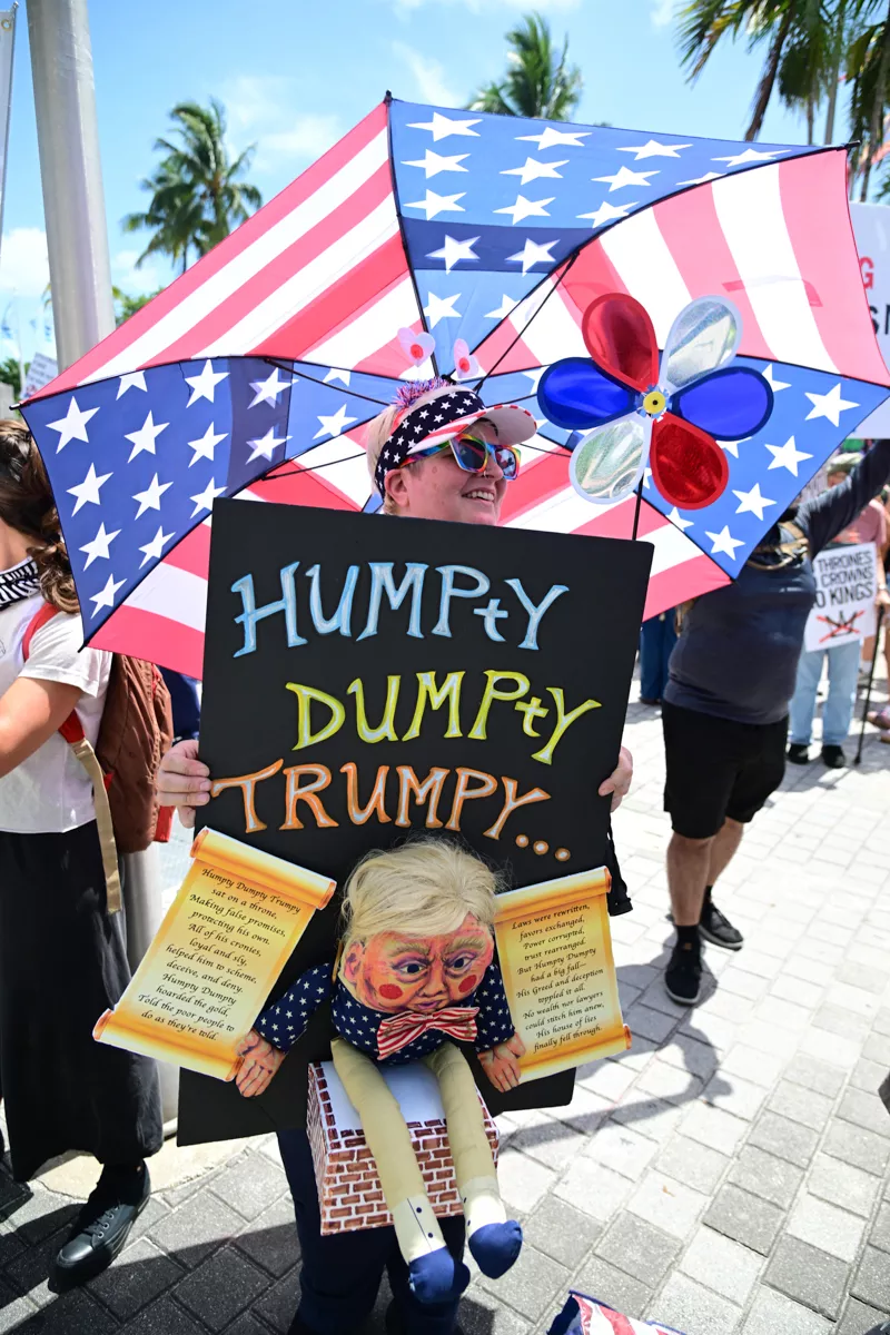 A woman holds up a sign, reading "Humpty Dumpty Trumpty" with an effigy of Donald Trump