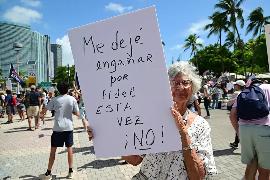 An elderly woman holds up a sign reading, "Me dejé engañar por Fidel esta vez. Esta vez ¡No!"