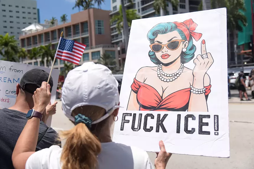 A woman holds an anti-ICE sign.