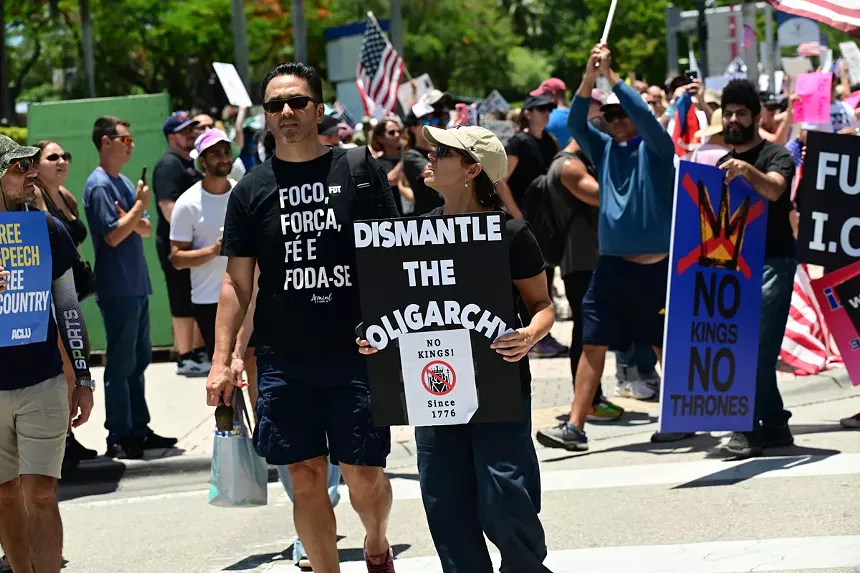 A woman holds a sign calling to "dismantle the oligarchy."
