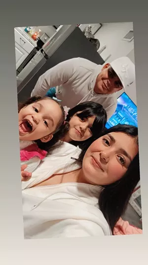 Two young girls smile alongside their parents.