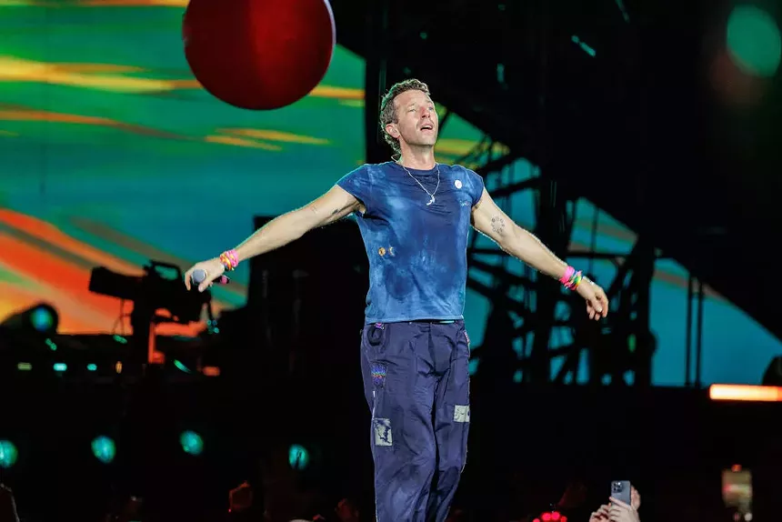 Coldplay singer with open arms on stage.