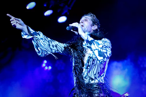 Man singing on stage under blue lights