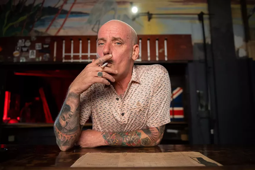 portrait of a man smoking a cigarette behind a bar