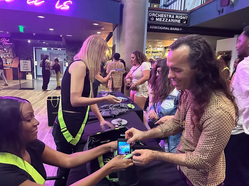 Concert attendees placing cellphones in locked pouches.