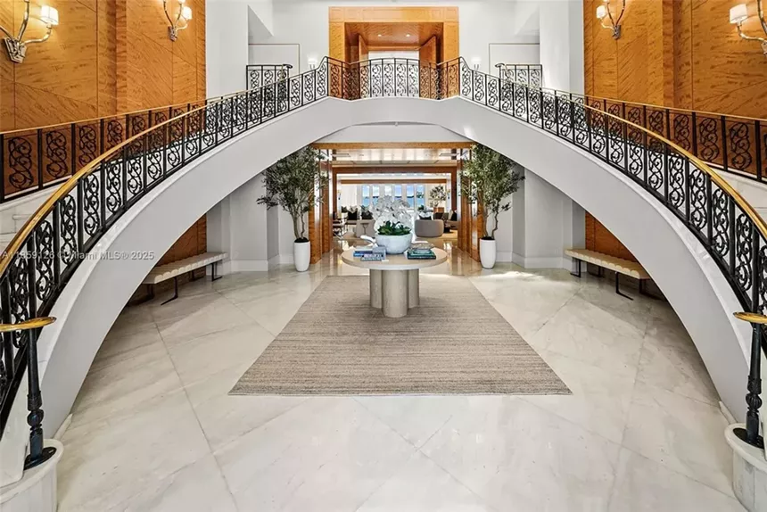 A sweeping bifurcated staircase stretches on either side of the home's entryway.