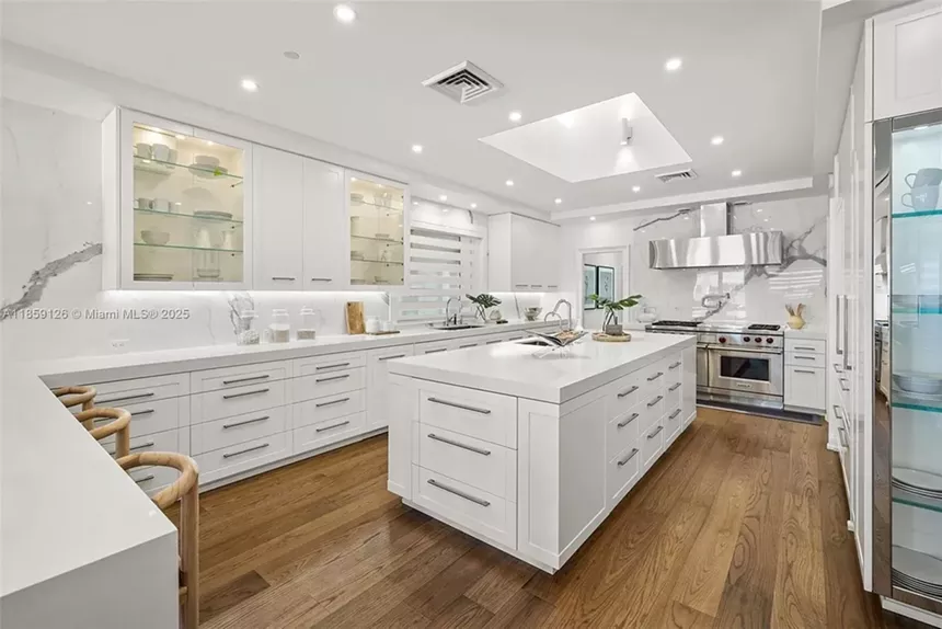 Pictured is a stark-white kitchen with stainless steel appliances.