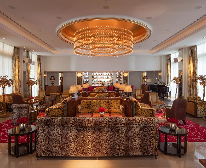 an opulent living room with a sizable chandelier and couches upholstered with different animal prints
