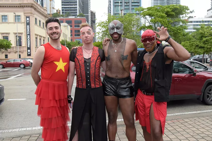 four Lady Gaga fans wearing black and red outfits pose in front of the street outside the arena