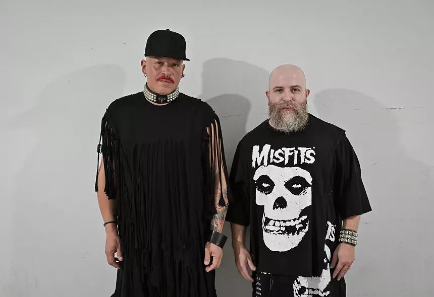 Two mean wearing black posing for the camera.