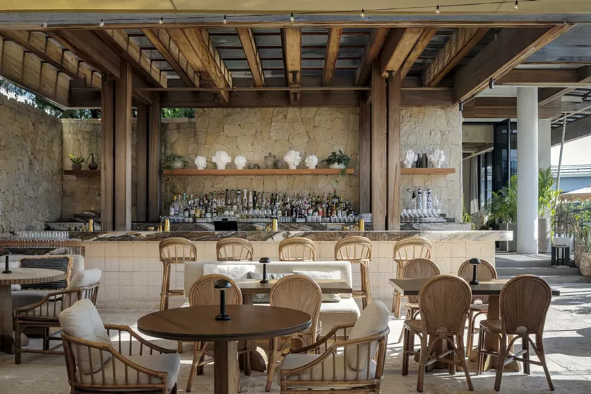a beach club with a bar and pastel beach chairs and couches