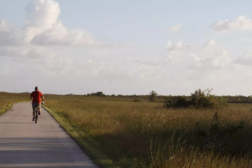 a man rides a bike on a trail in the middle of a prairie
